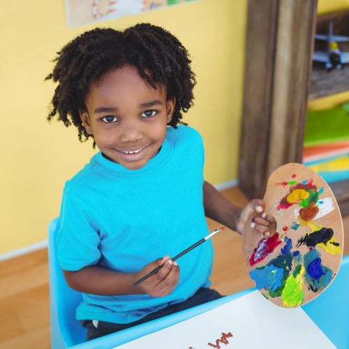 Smiling child creating a picture at a table